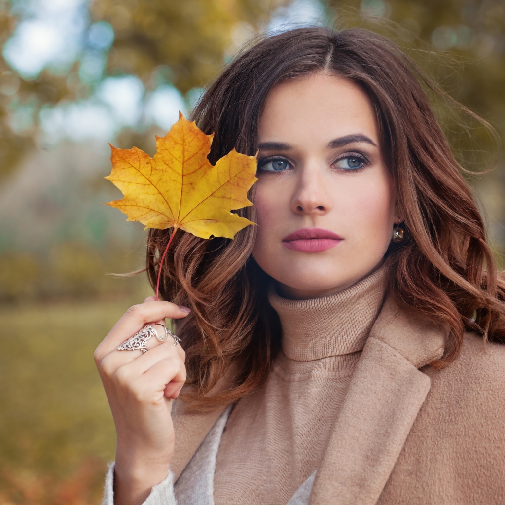 Красивая молодая девушка шатенка с желтым листом в руке