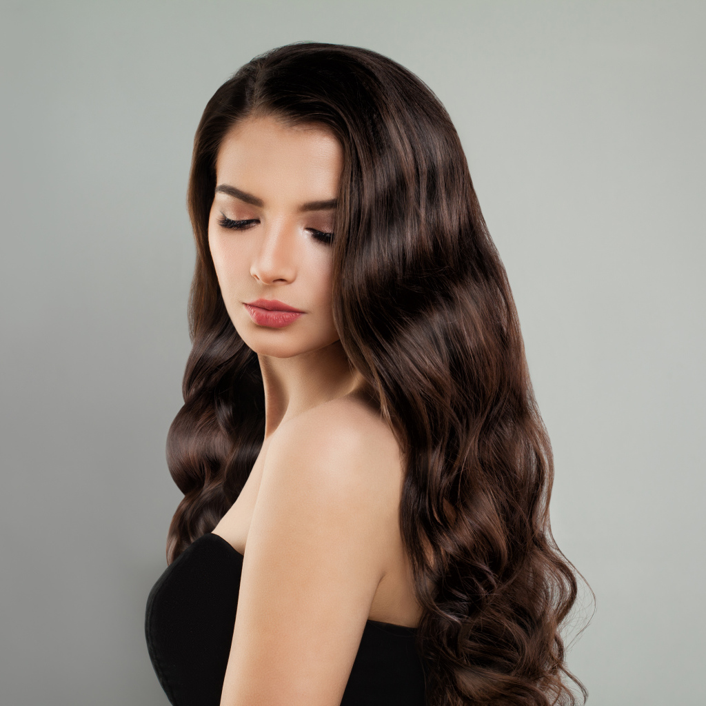 Красивая молодая длинноволосая девушка брюнетка на сером фоне