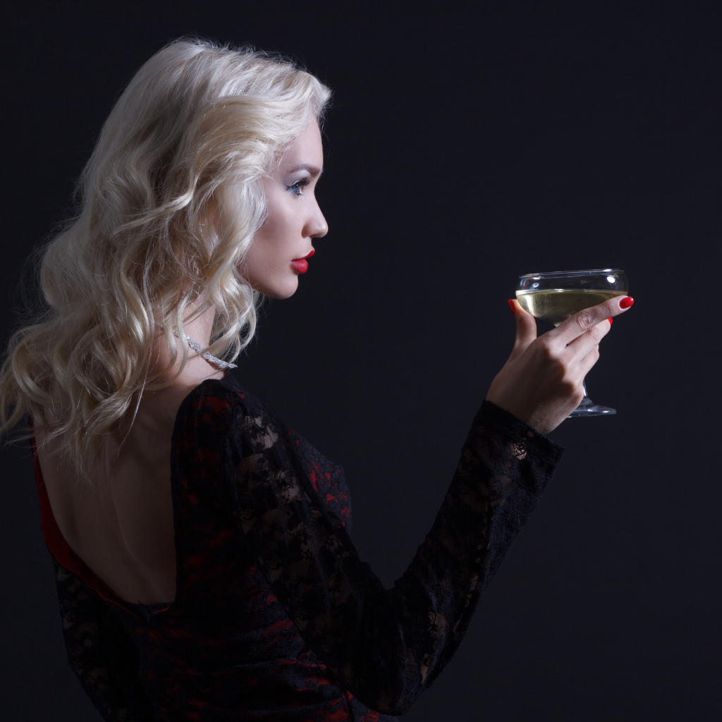 Блондинка с бокалом мартини в руках сером фоне 