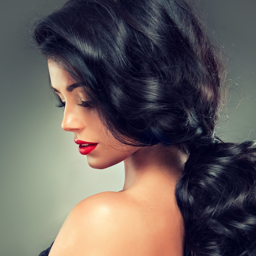 Девушка брюнетка с красивыми волосами на сером фоне