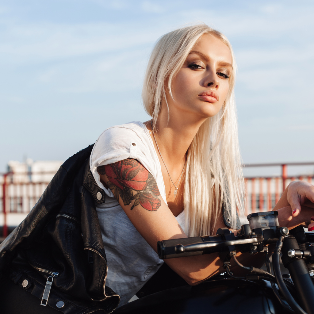 Брутальная блондинка с татуировкой на руке на мотоцикле 