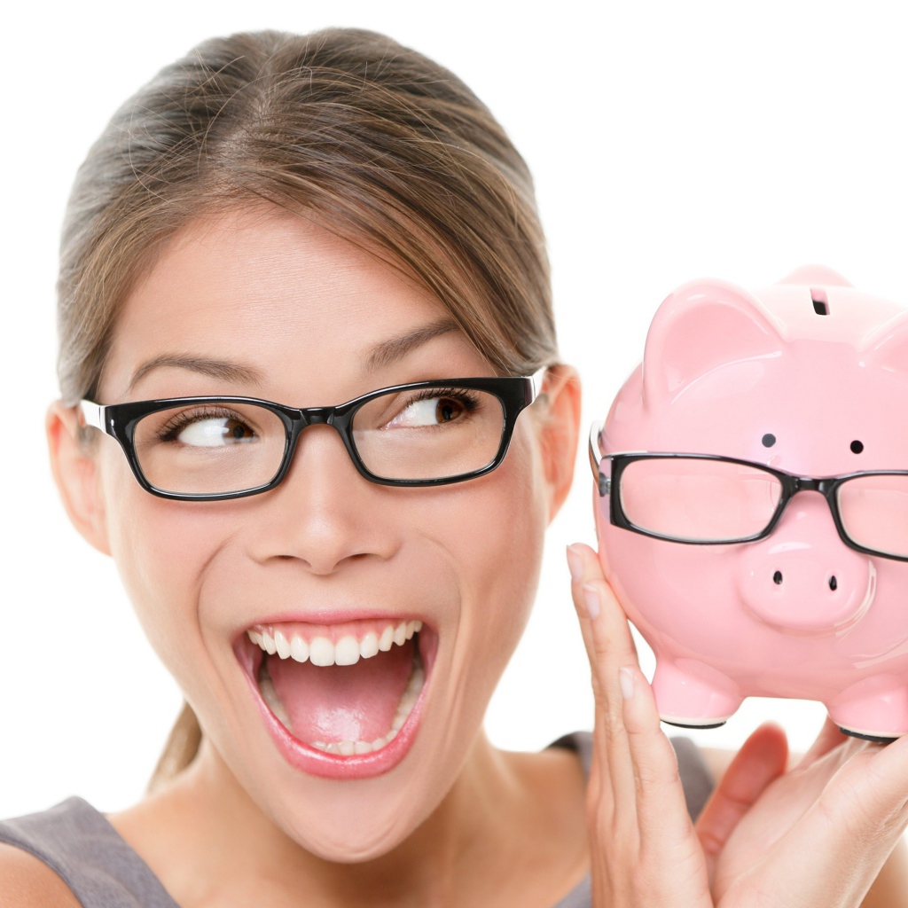 Веселая девушка в очках с копилкой в руках на белом фоне