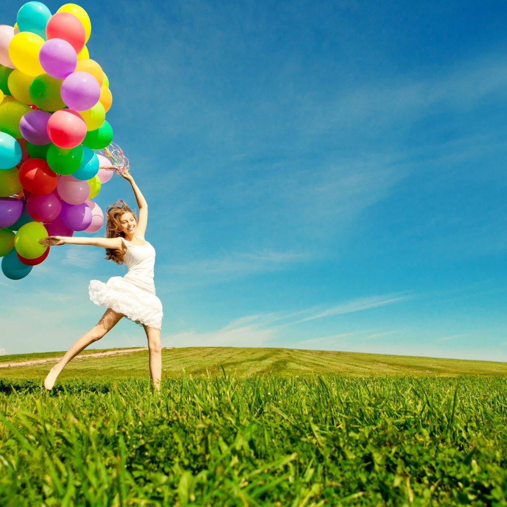 Веселая девушка в белом платье с разноцветными воздушными шариками