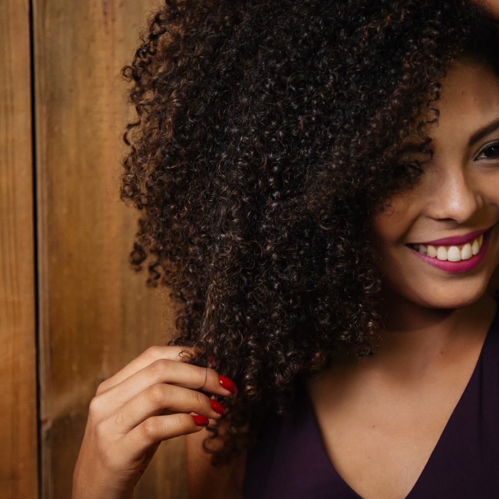 Кучерявая темнокожая девушка с красивой улыбкой 