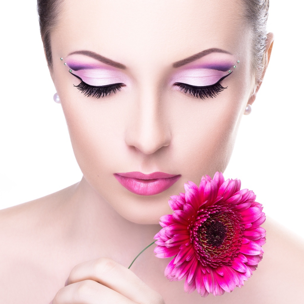 Нежная девушка с розовым цветком герберы на белом фоне