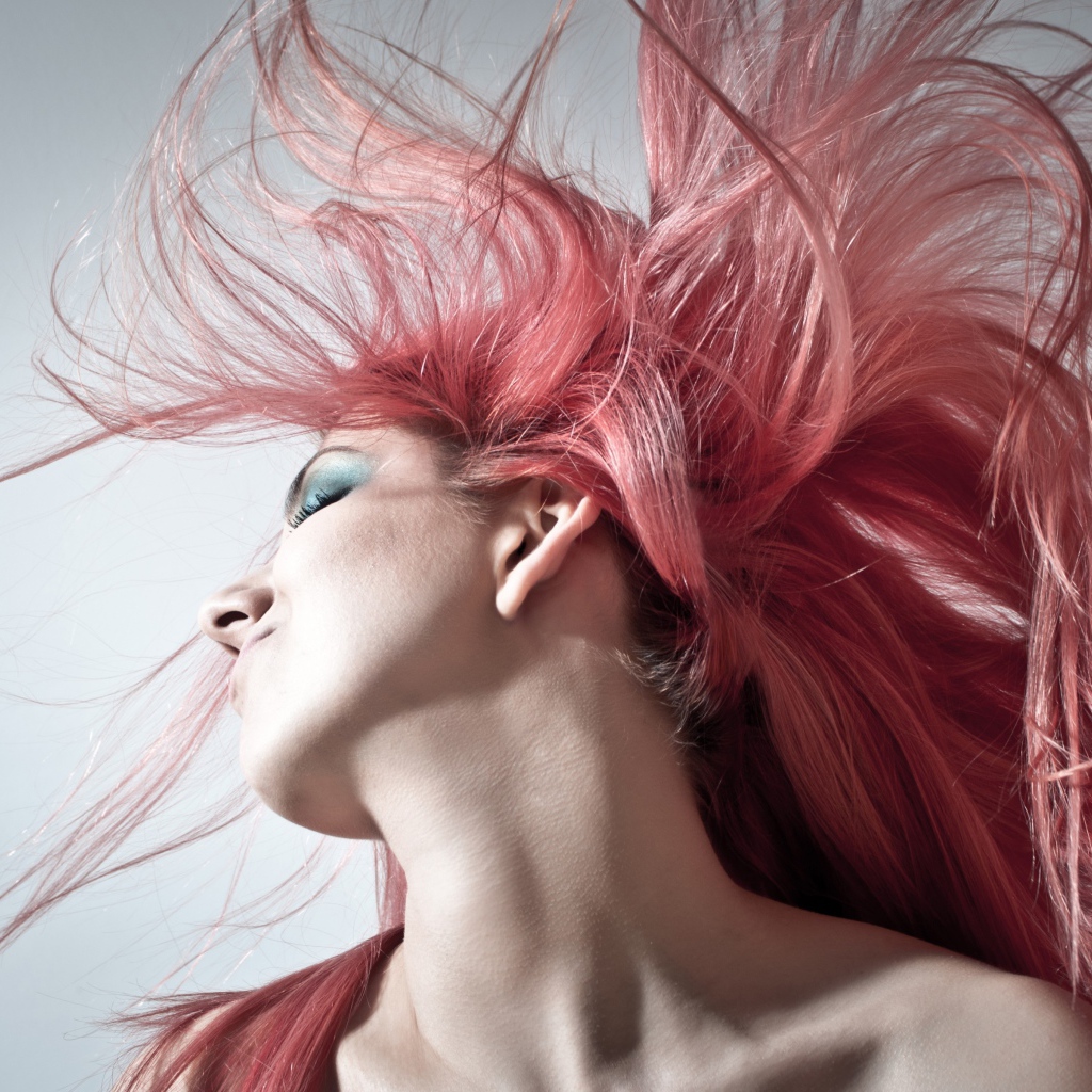 Девушка с распущенными розовыми волосами на сером фоне