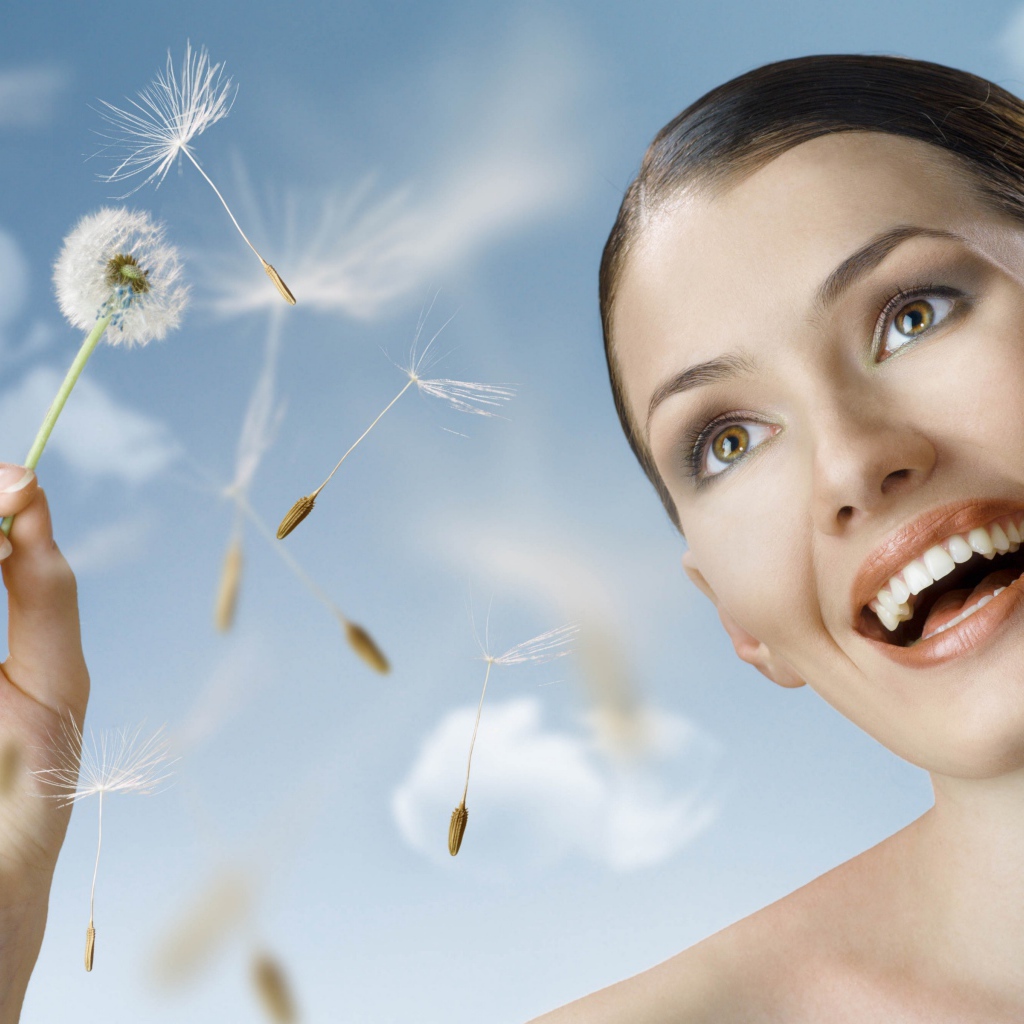 Счастливая девушка с одуванчиком в руке 