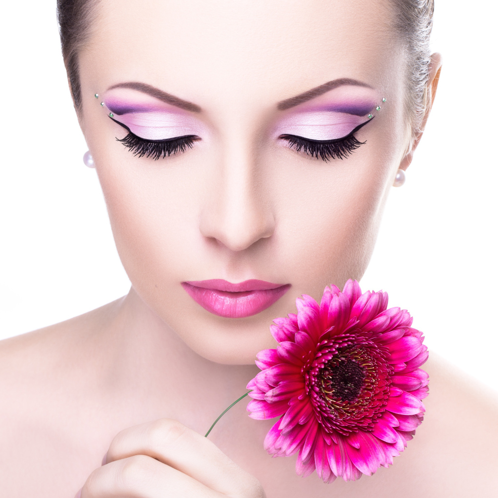 Девушка модель с нежным макияжем с розовым цветком герберы в руке