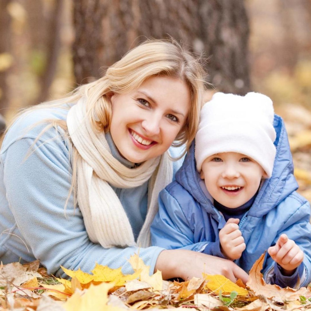 Мать с сыном лежат на листве осенью