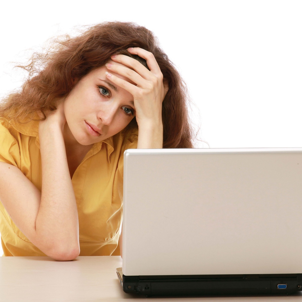 Грустная девушка сидит возле ноутбука 