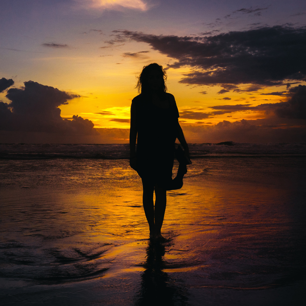 Silhouette of a beautiful girl on the beach at sunset