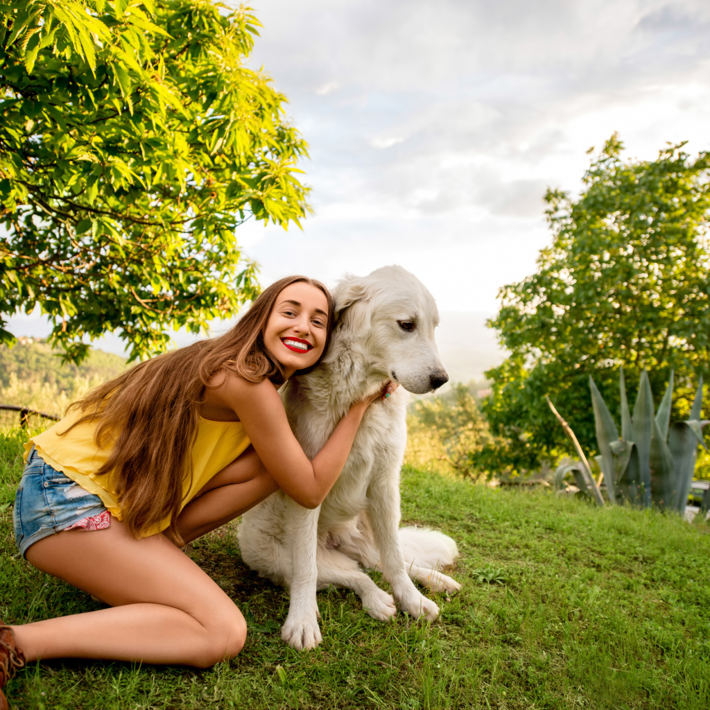 Улыбающаяся шатенка с золотистым ретривером на зеленой траве летом