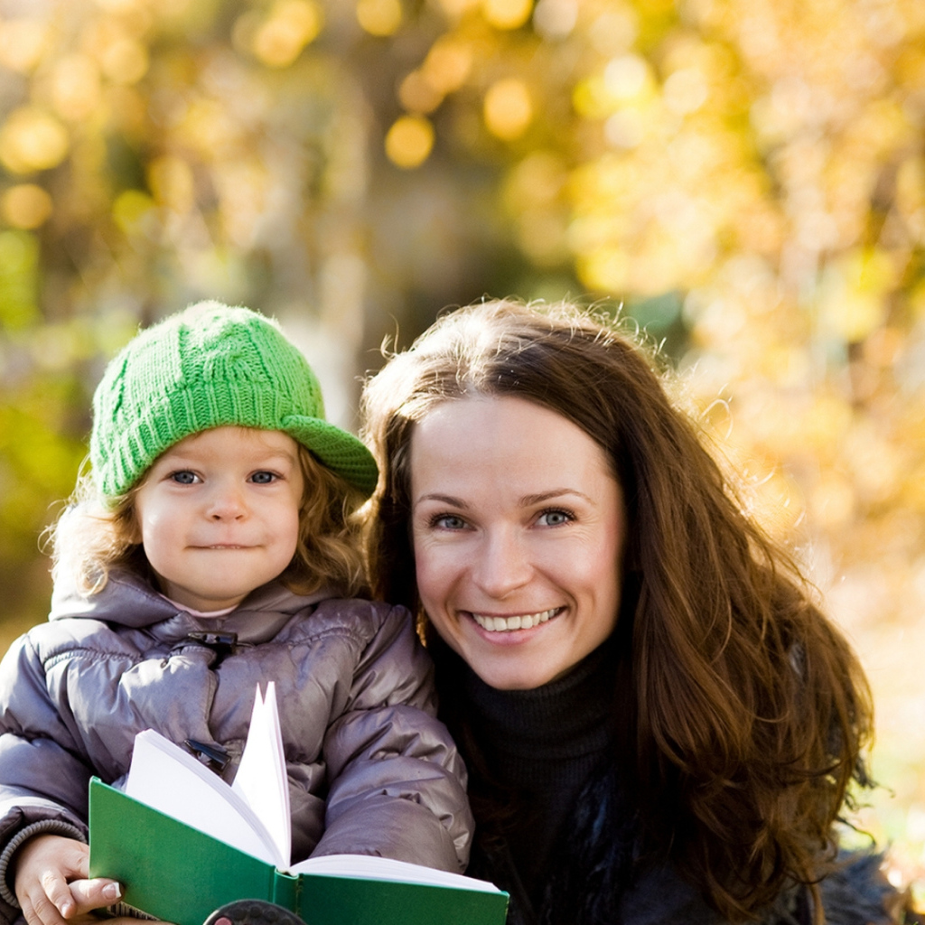 Улыбающаяся девушка с девочкой читают книгу