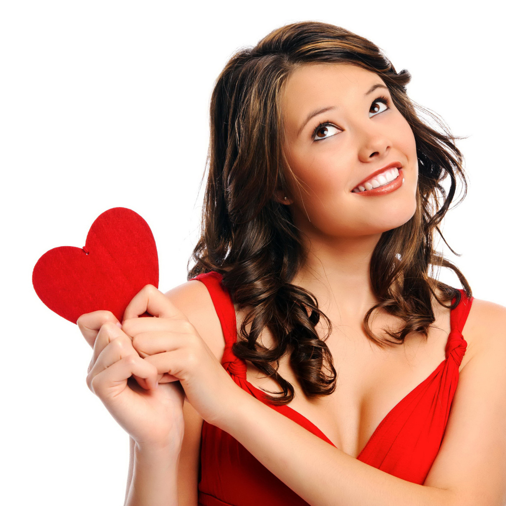 Улыбающаяся девушка с красным сердечком в руках на белом фоне