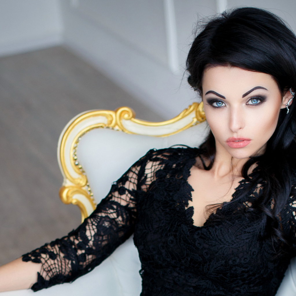 Эффектная брюнетка в черном платье сидит в кресле