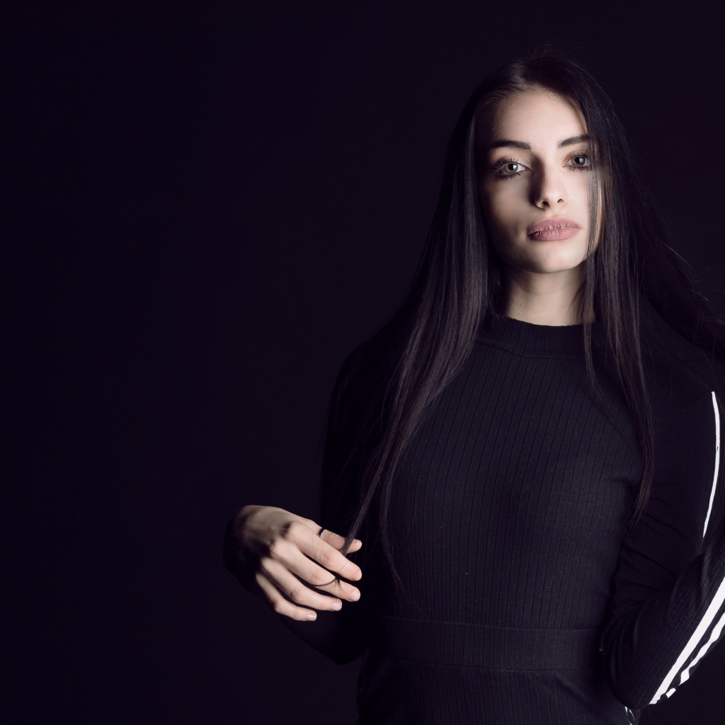 Эффектная брюнетка в черном наряде на черном фоне