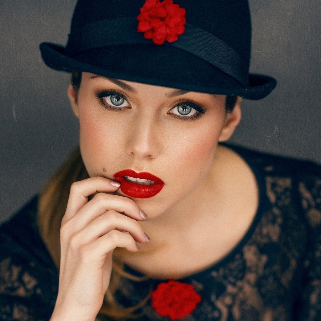 Стильная девушка с ярким макияжем в черной шляпе 