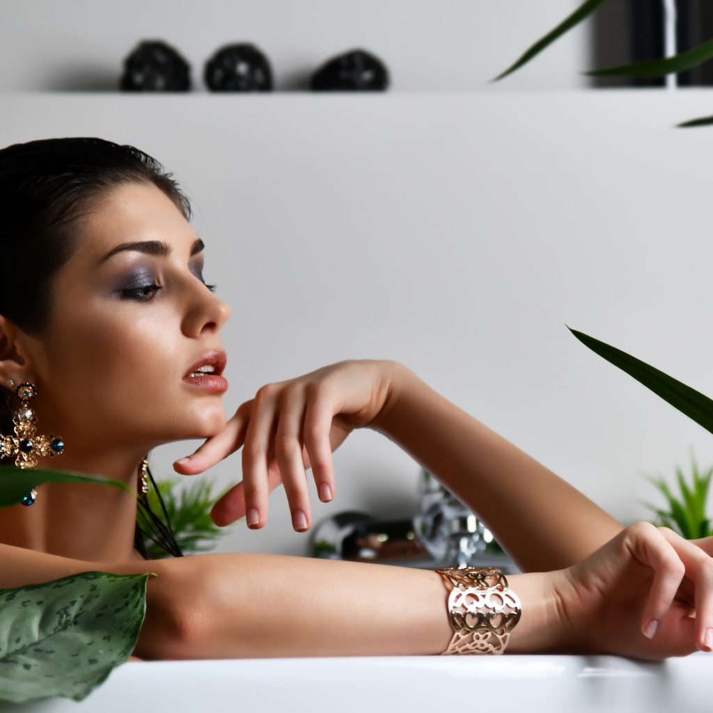 Девушка в дорогих украшения лежит в ванной