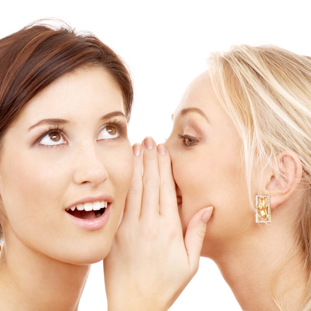 Две подруги делятся секретами на белом фоне 