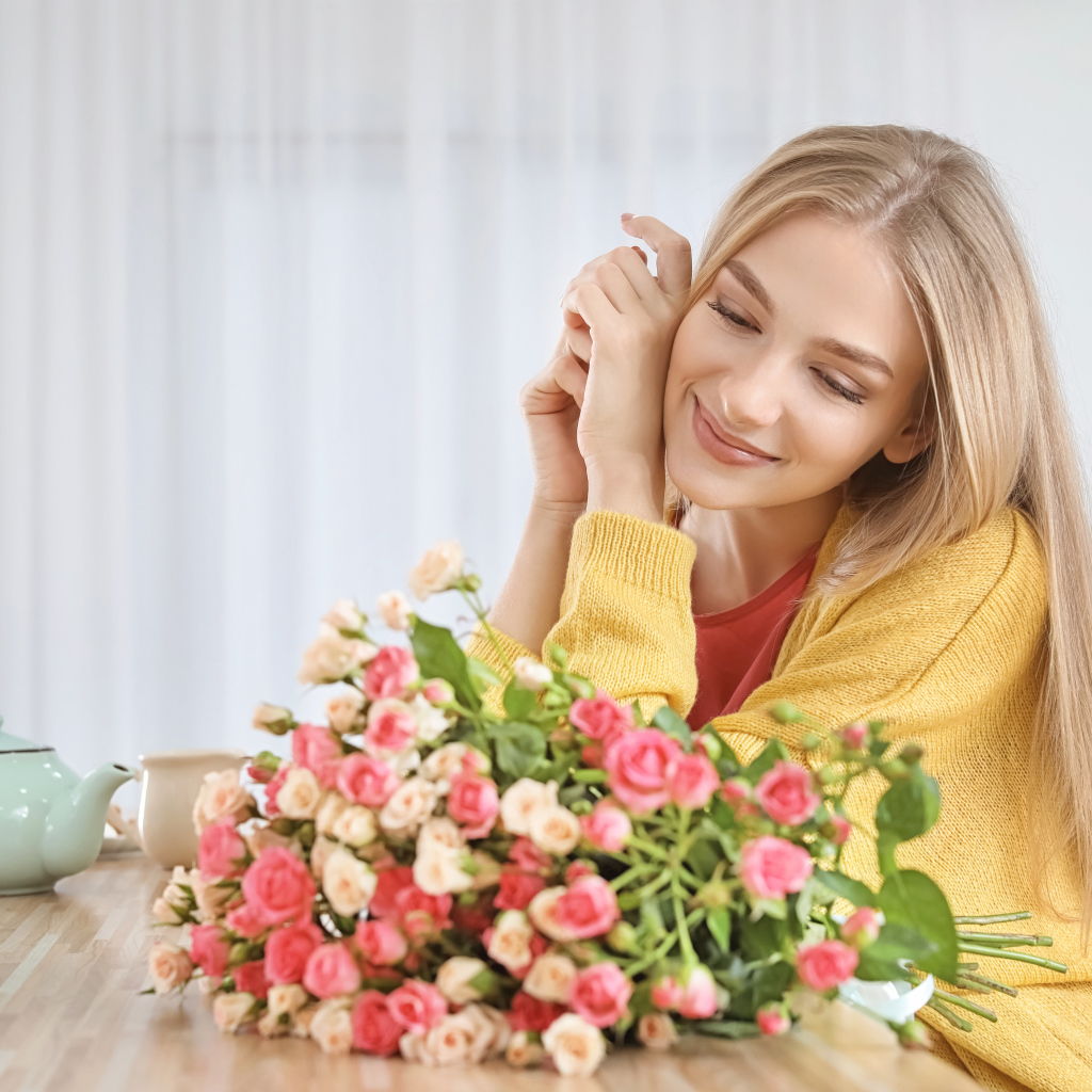 Молодая блондинка с букетом роз на столе