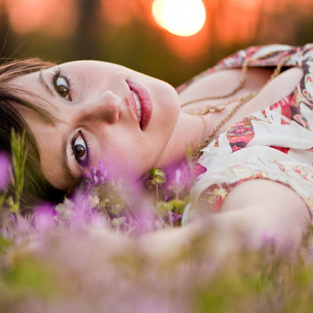 Молодая кареглазая девушка лежит на траве