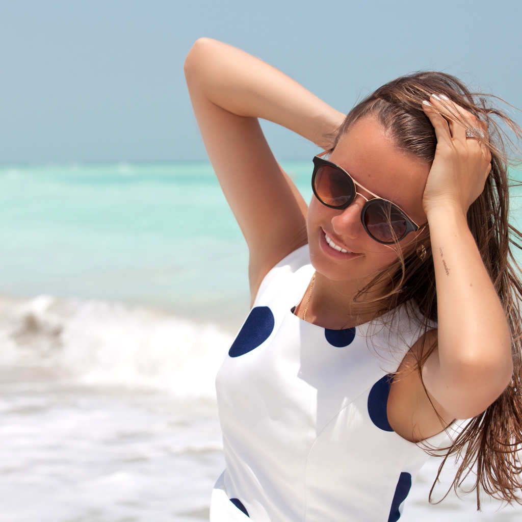 Молодая шатенка в солнечных очках у моря