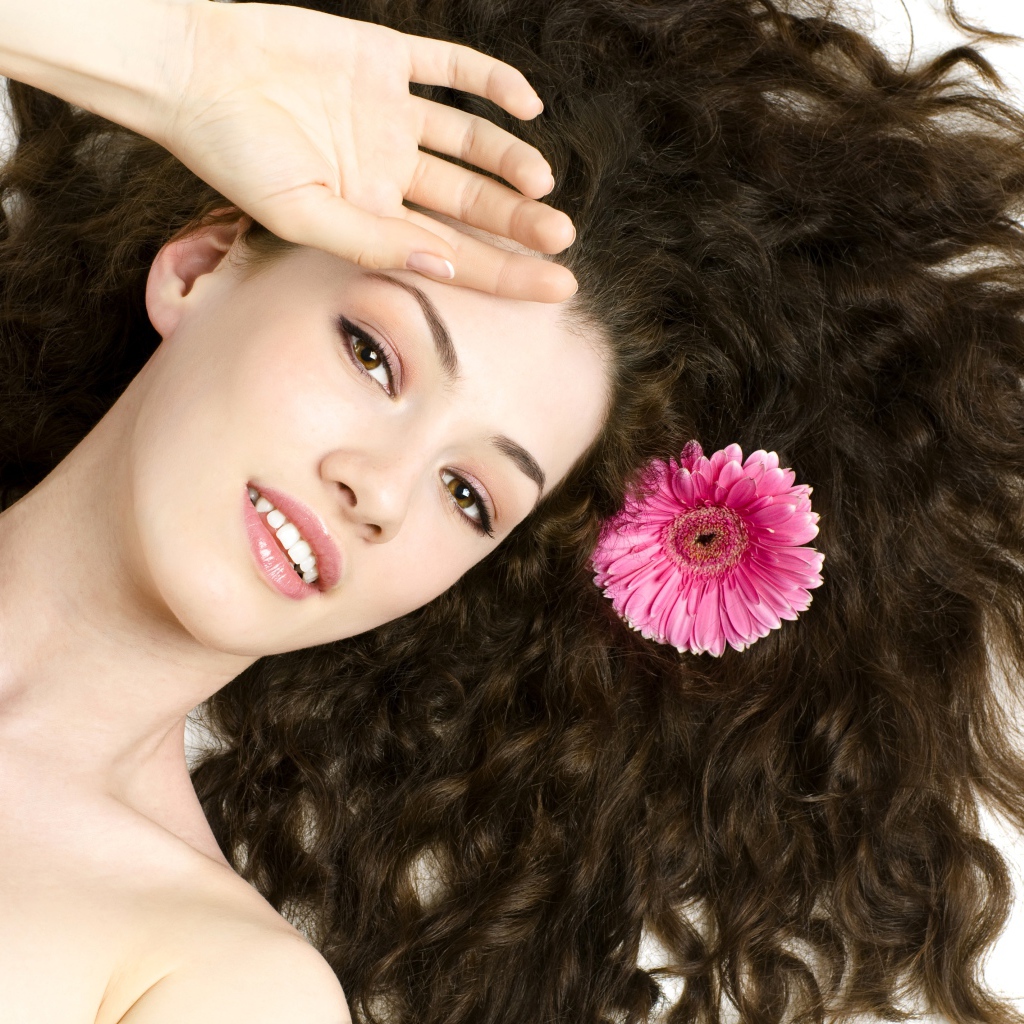Молодая шатенка с розовым цветком герберы в волосах