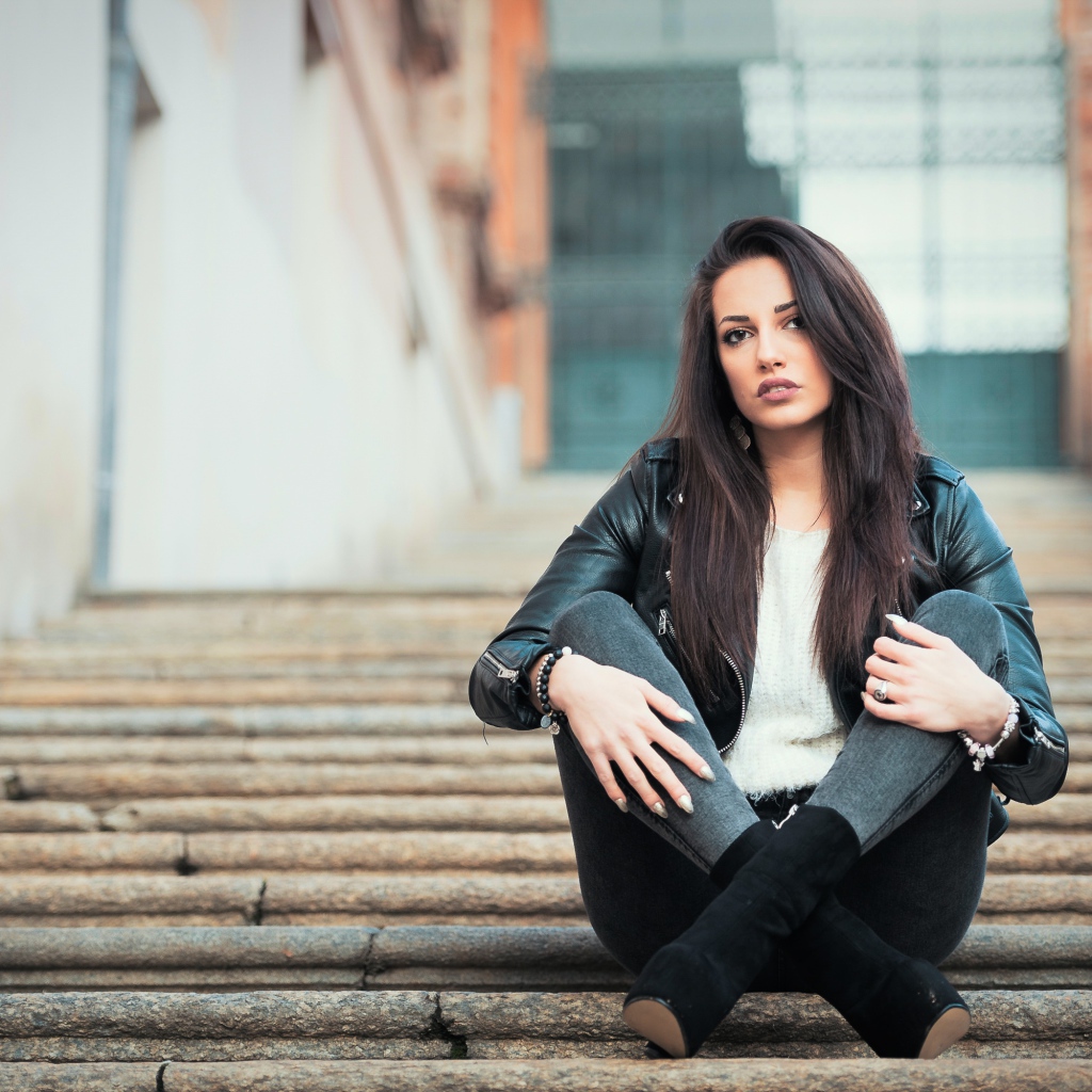 Молодая брюнетка сидит на ступеньках