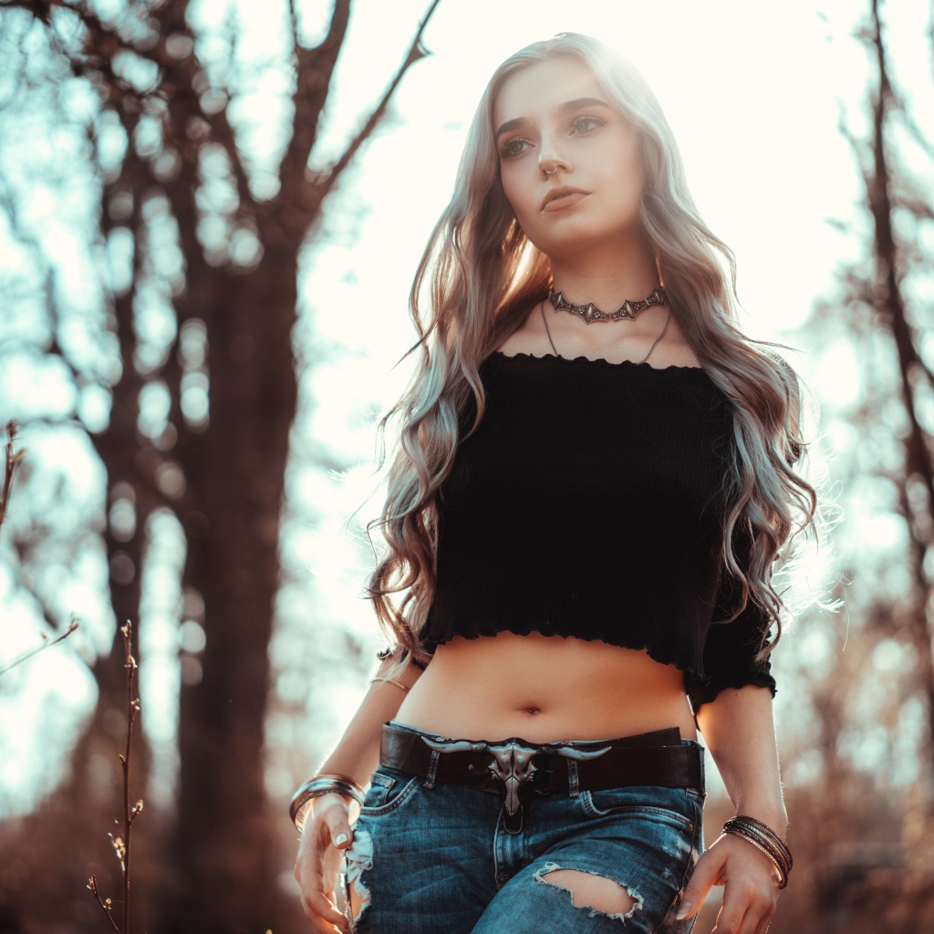 Молодая девушка в рваных джинсах с пирсингом в носу