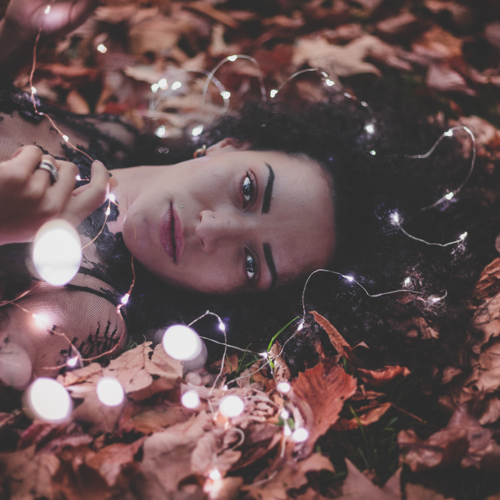 Молодая девушка лежит с гирляндой на желтых листьях