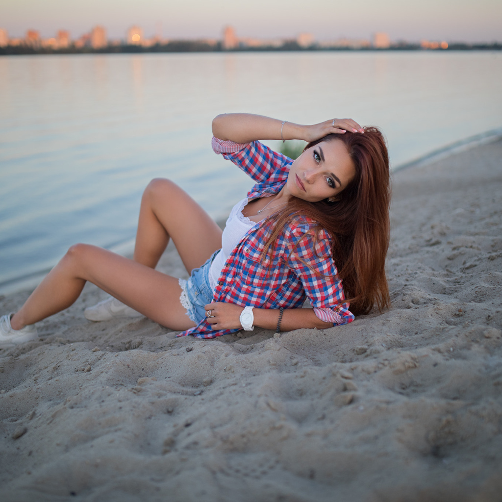Молодая девушка лежит на песке у реки