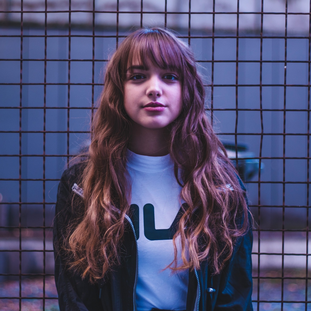 Молодая девушка на фоне железной сетки