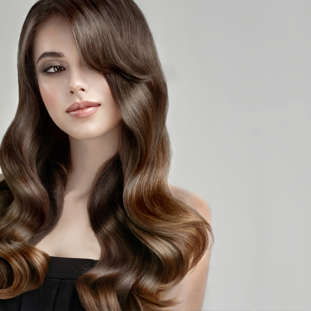 Молодая девушка с красивыми длинными волосами на сером фоне