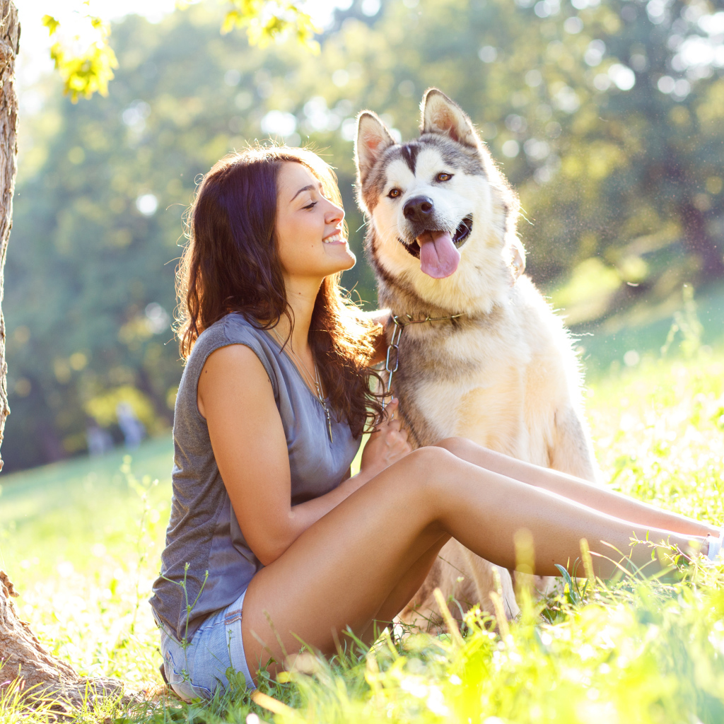 Молодая девушка с хаски сидят под деревом летом