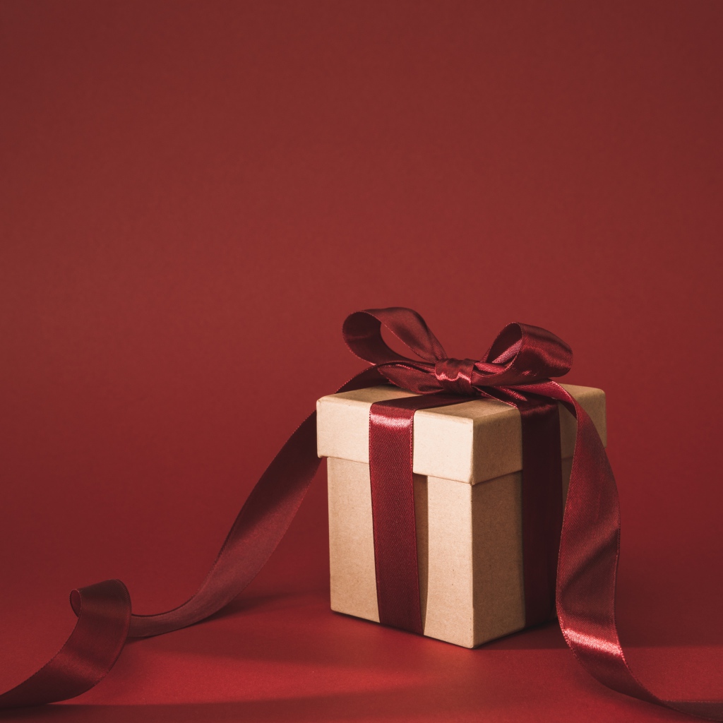 Gift box with red bow on red background