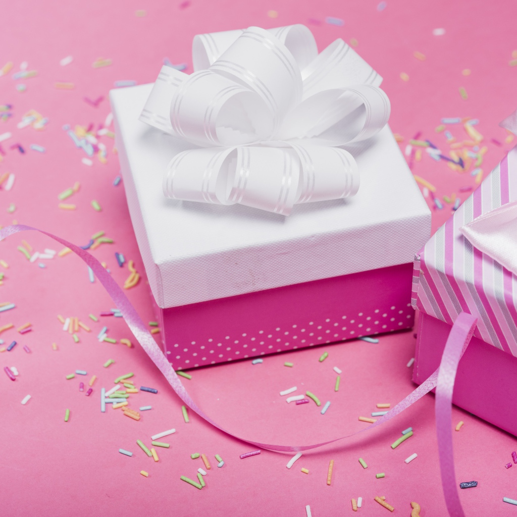 Две подарочные коробки с бантами на розовом фоне