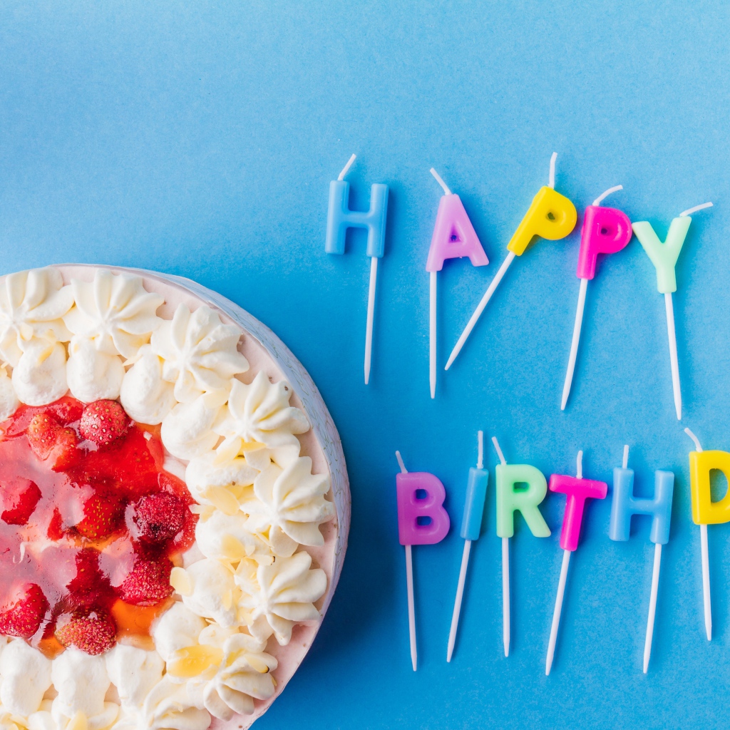 Красивый торт с кремом и клубникой на голубом фоне со свечами на день рождения