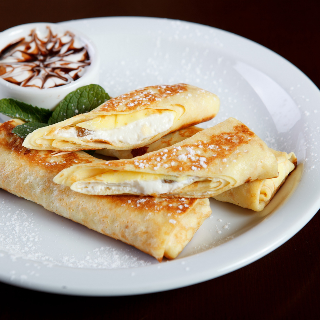 Блины с творогом и сметаной на белой тарелке на Масленицу