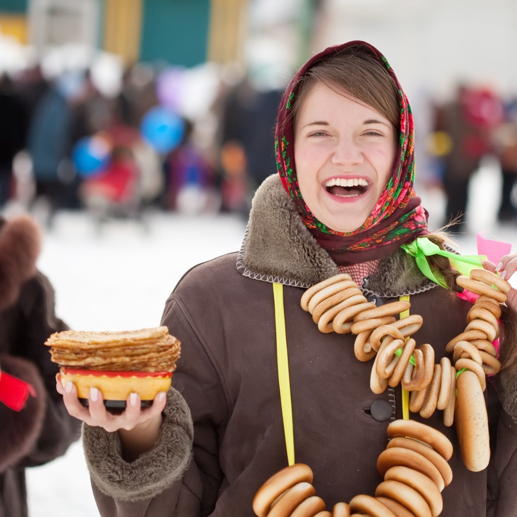Улыбающаяся девушка с угощениями на праздник Масленица 2018
