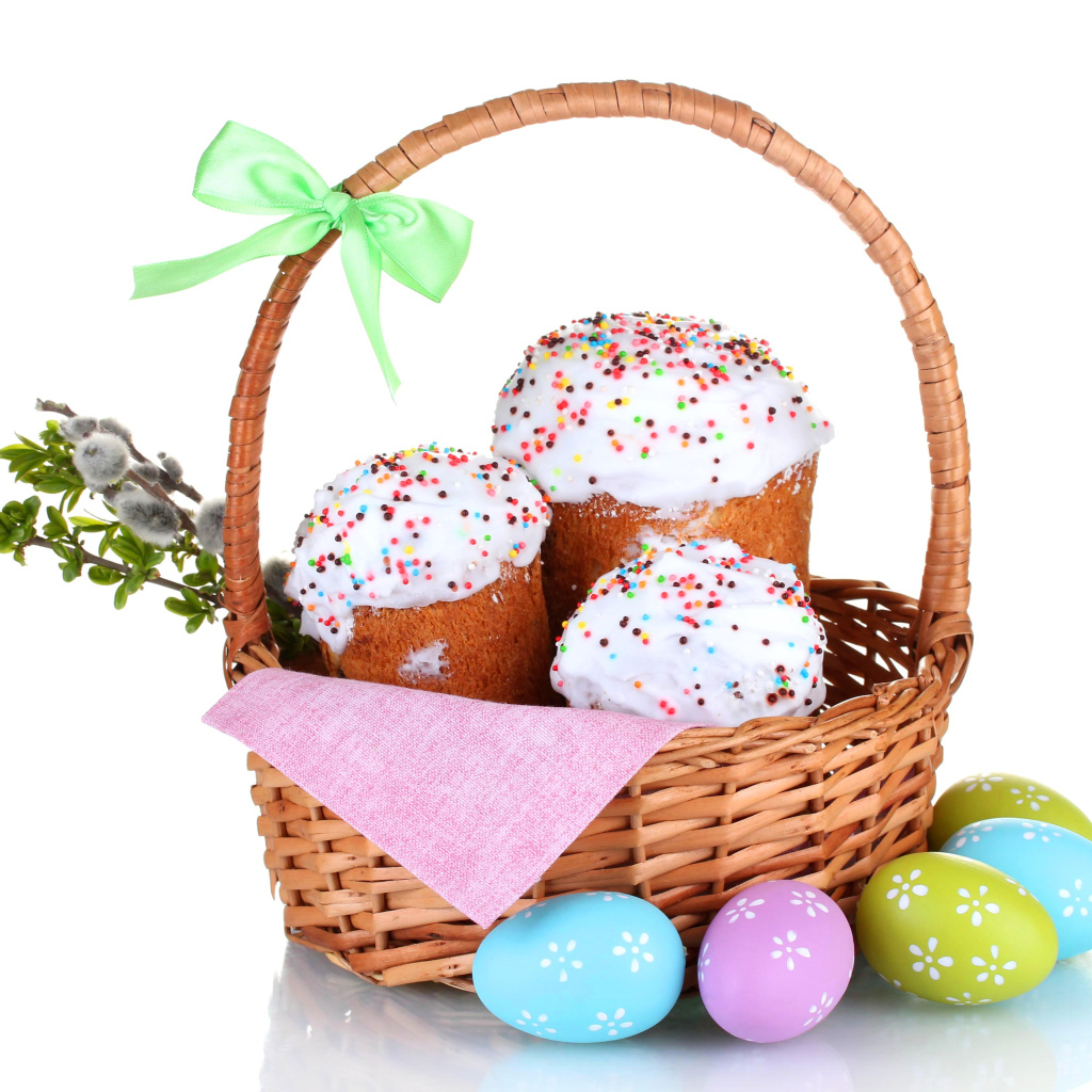 Пасхальные куличи в корзине с крашеными яйцами на белом фоне