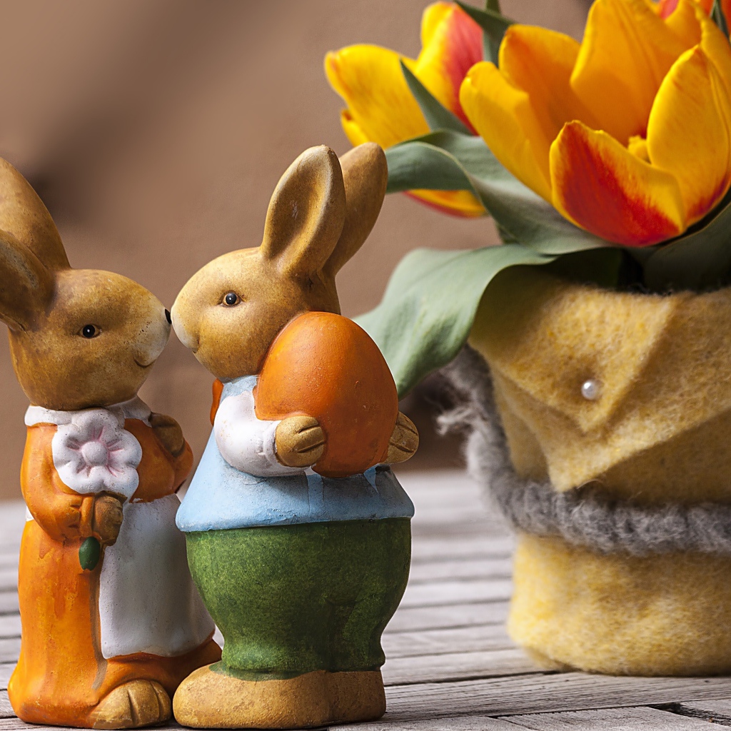 Статуэтки пасхальных кроликов на столе с тюльпанами