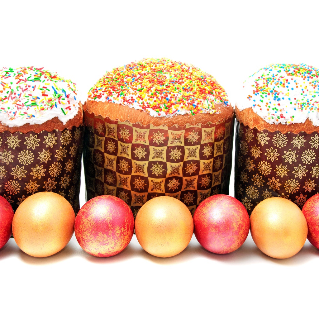 Три пасхальных кулича с крашеными яйцами на белом фоне на праздник Пасха