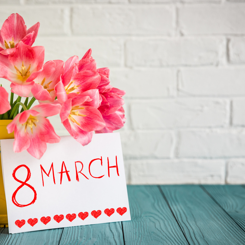 Букет тюльпанов и открытка на фоне стены на 8 марта