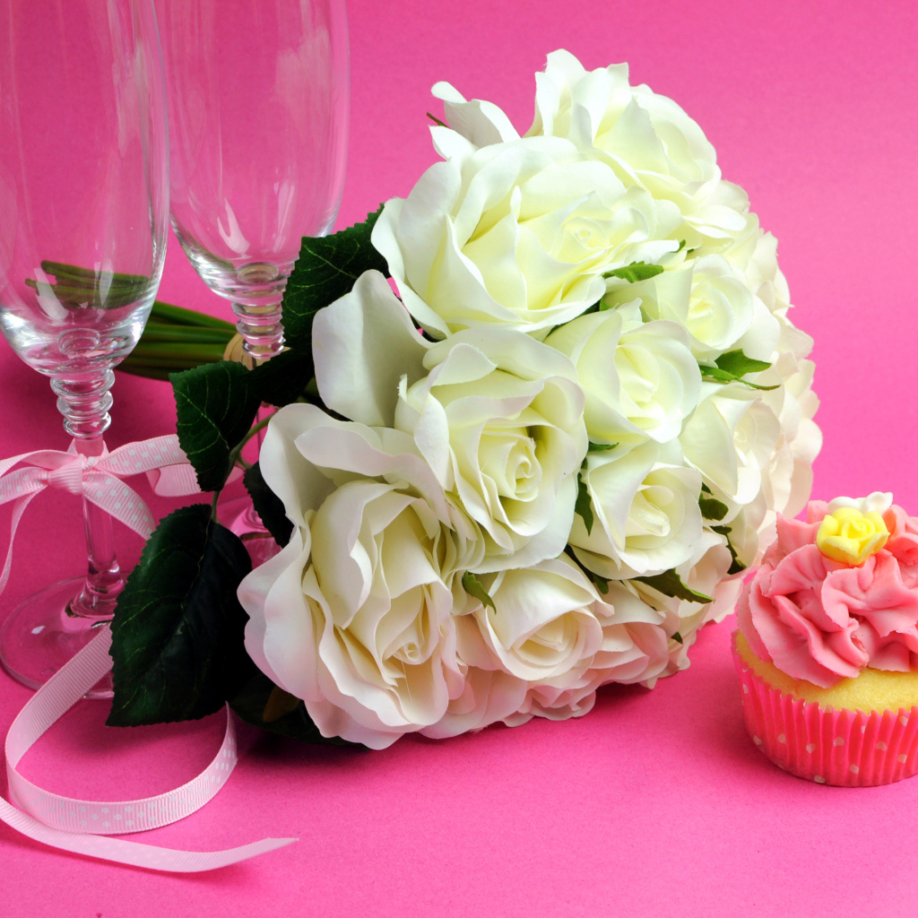 Букет белых роз, пирожное и два бокала на розовом фоне на 8 марта