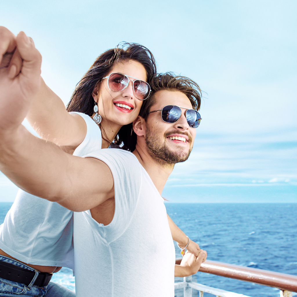 Влюбленная пара держится за руки на фоне моря