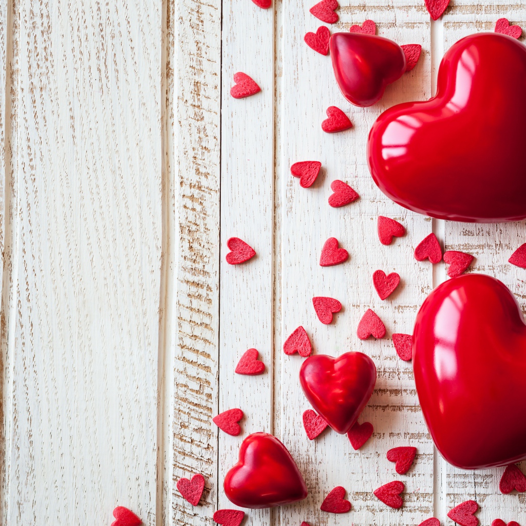 Большие и маленькие  красные  сердечки на деревянном фоне