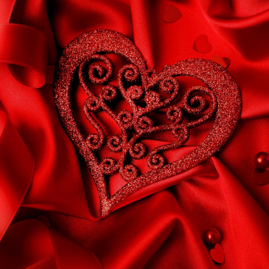 Блестящее сердце на красной атласной ткани 