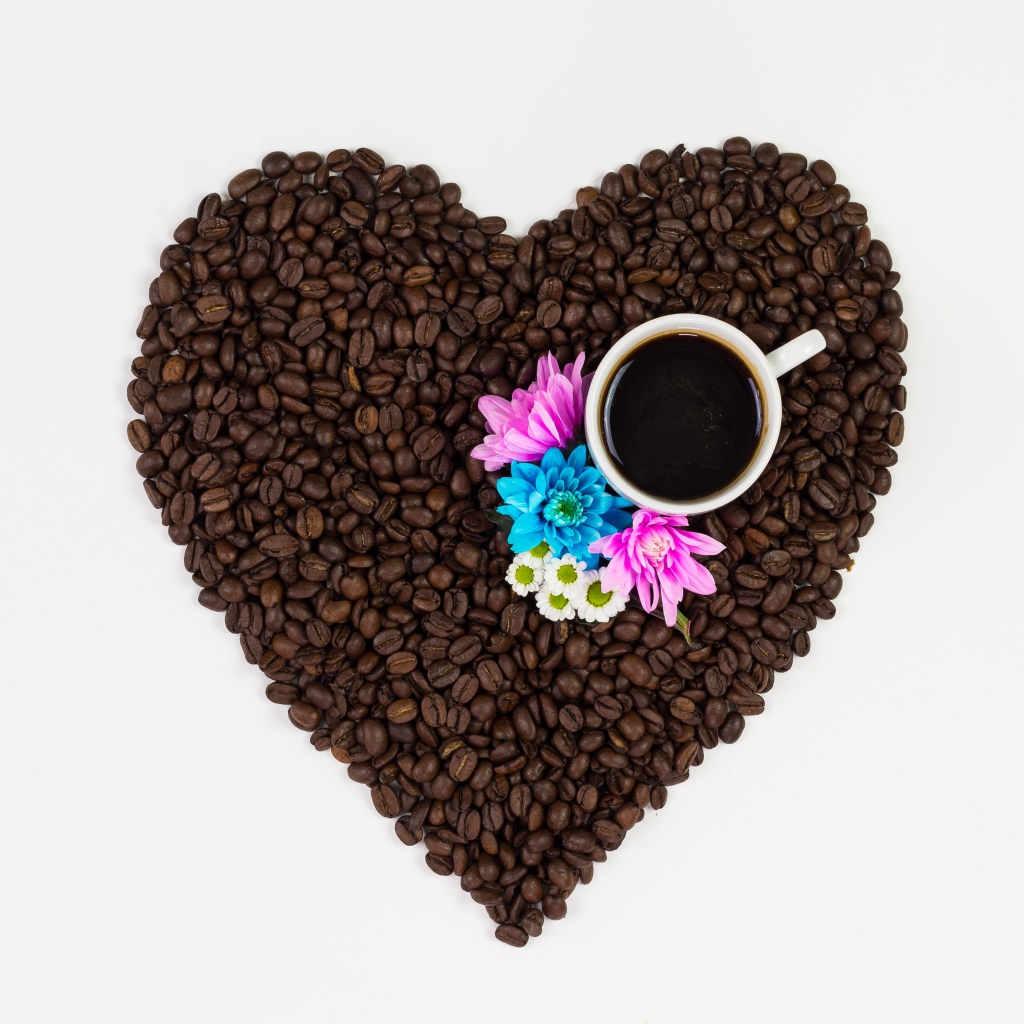 Сердце из кофейных зерен с чашкой на белом фоне