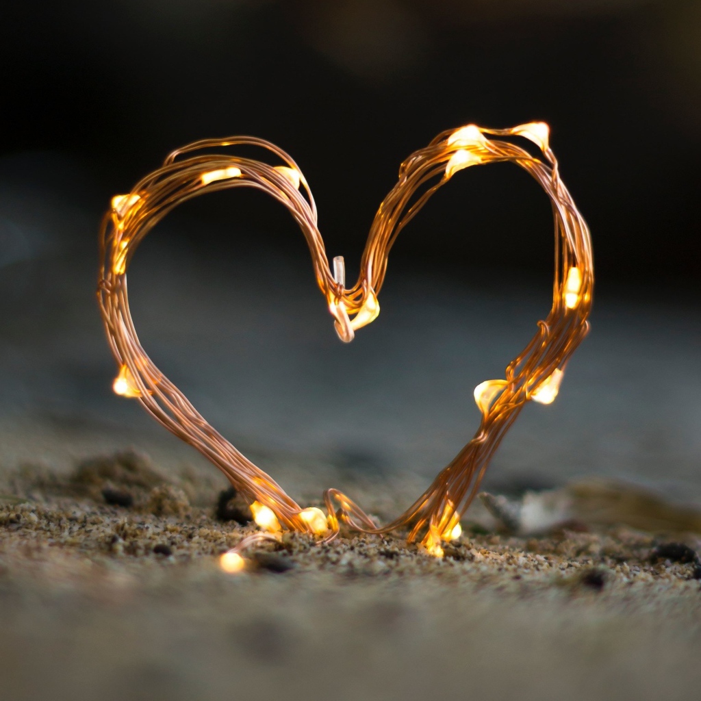 Сердце из гирлянды на песке