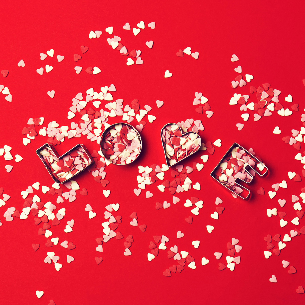 Надпись любовь из маленьких  сердечек на красном фоне